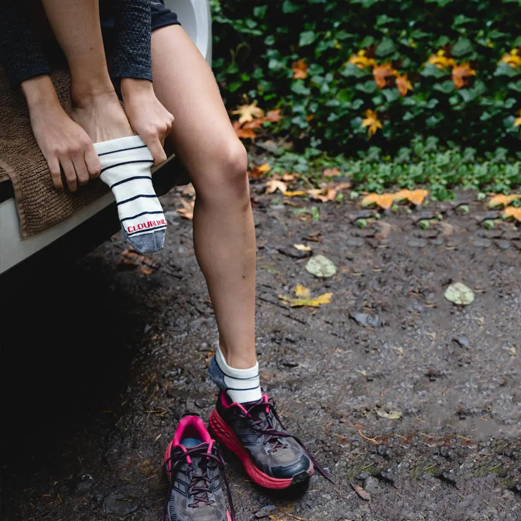 Women sitting in open hatchback pulling on Cloudline no show merino wool running socks.