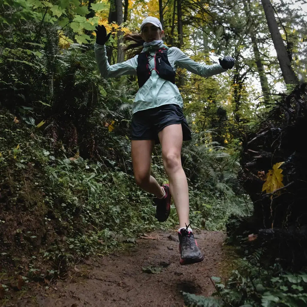 Women wearing Cloudline merino wool trail running socks in mid stride running down a trail.