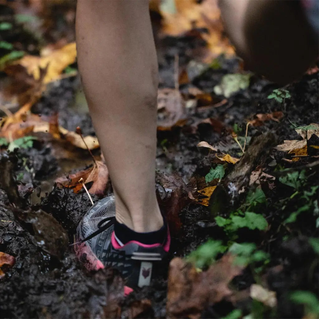 Runner wearing Cloudline merino wool running socks splashing through muddy puddle.