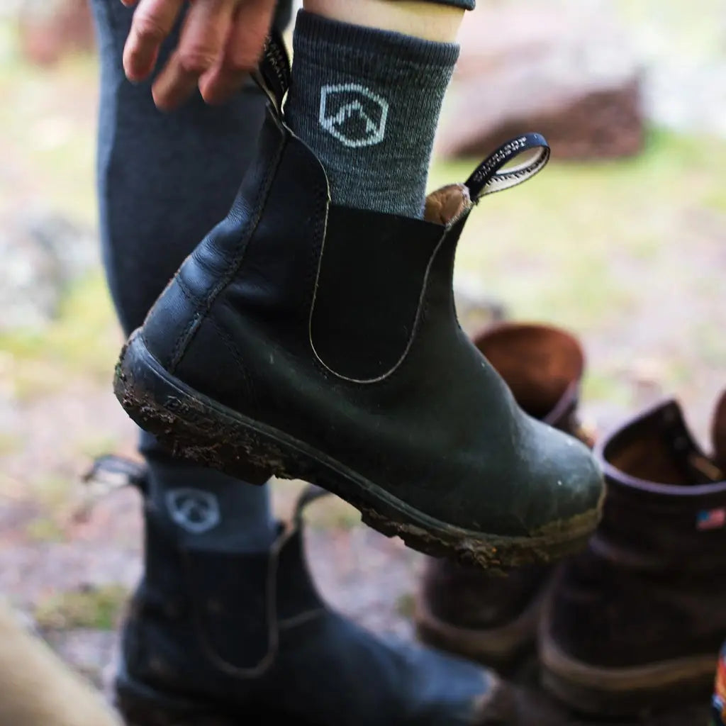 Women wearing Cloudline 1/4 Top Merino Wool Running Socks and putting on fashionable boots.