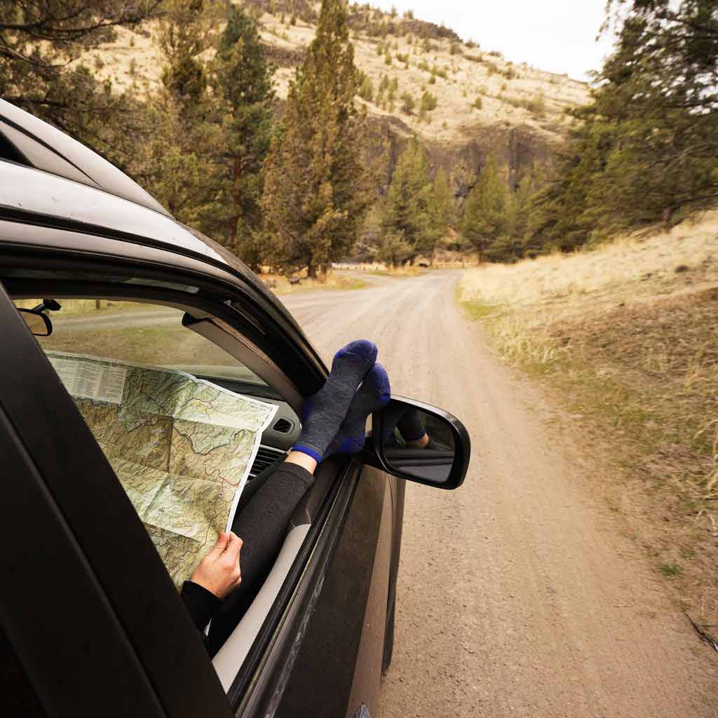 SUV passenger wearing Cloudline socks while checking a map for directions to the trailhead.