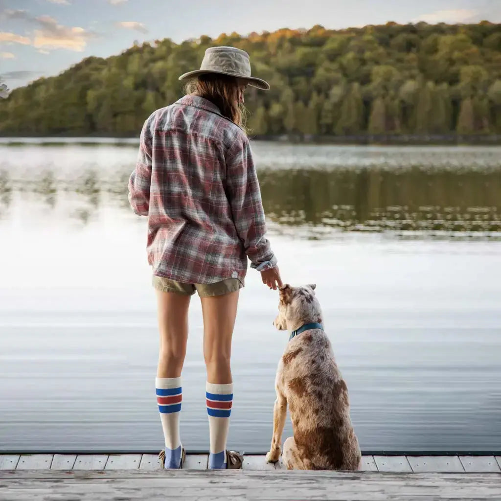 Women wearing Cloudline merino wool compression socks standing on dock with her dog watching the sunrise.