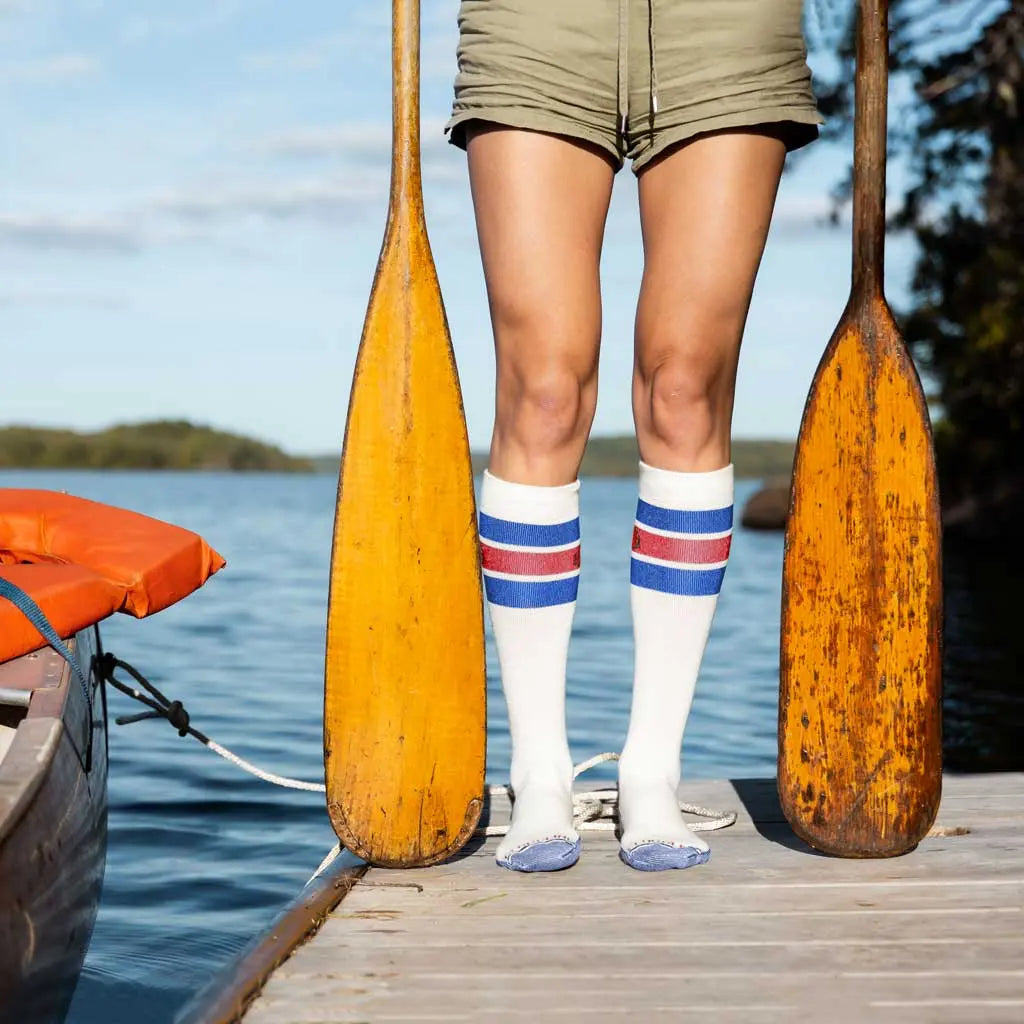 Women wearing Cloudline merino wool compression socks standing on dock with paddles next to tied up canoe.