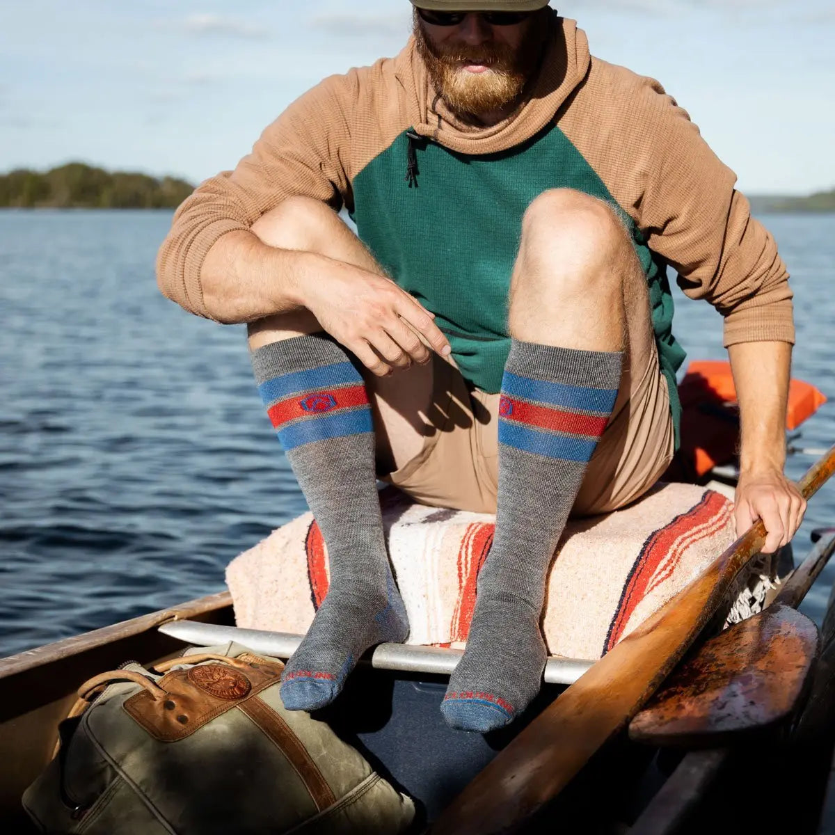 Bearded man wearing Cloudline merino wool compression socks sitting in rowboat.