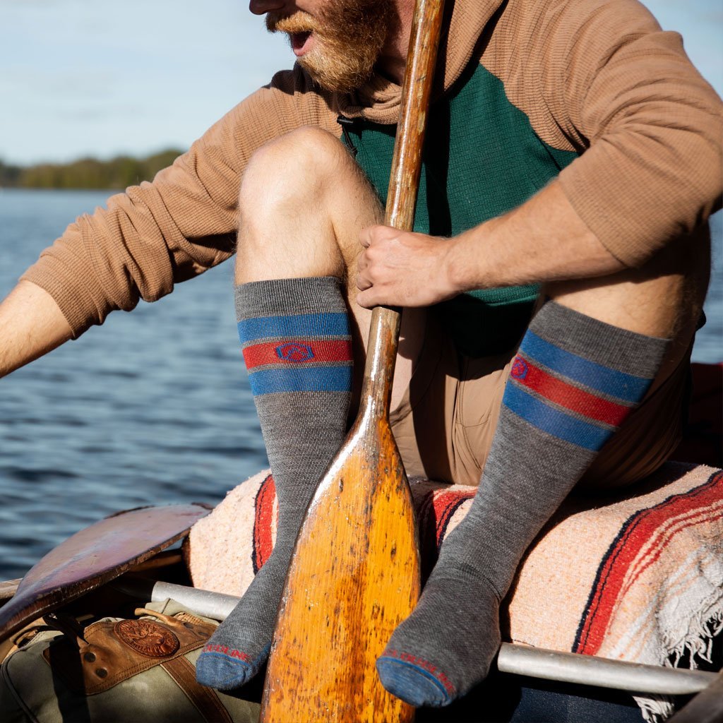 Man wearing Cloudline compression socks sitting in boat looking at something in water.