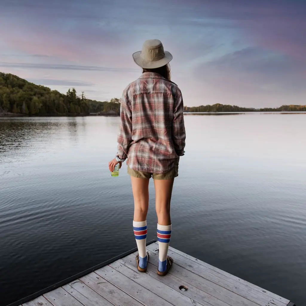 Women wearing Cloudline merino wool compression socks standing on dock at sunset with back to camera.