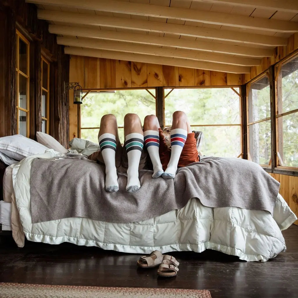 Man and women laying on bed with knees up wearing Cloudline merino wool compression socks.