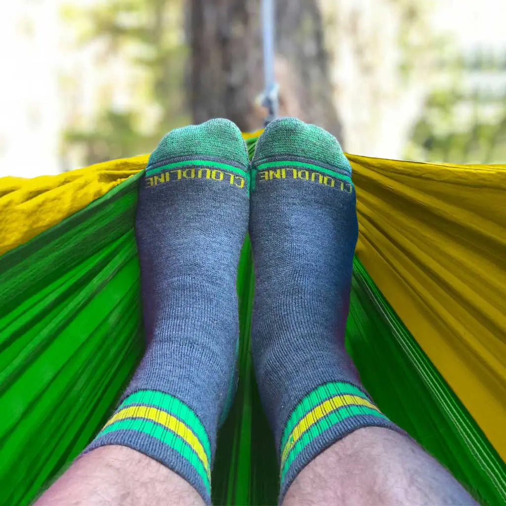 Camper wearing cozy Cloudline merino wool hiking socks while relaxing in hammock.
