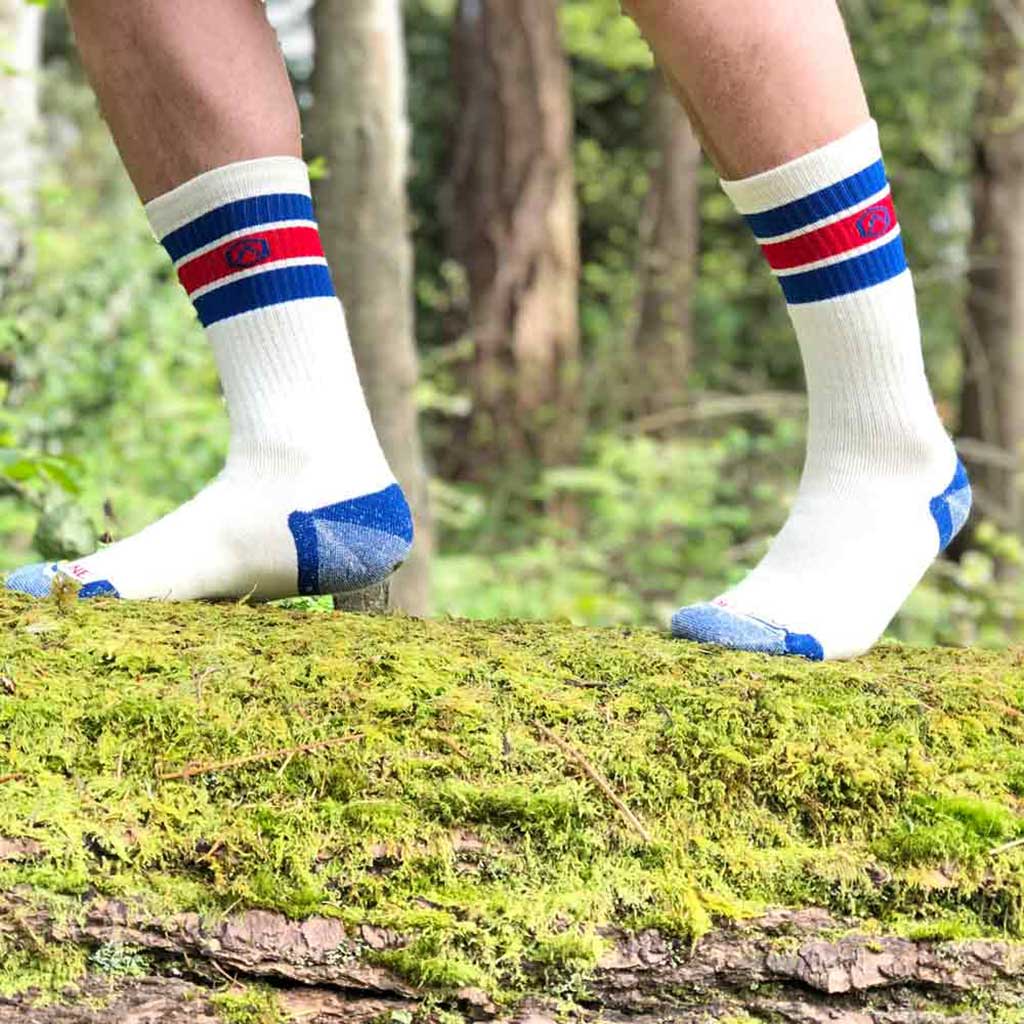 Man walking across moss covered log wearing Cloudline merino wool hiking socks.