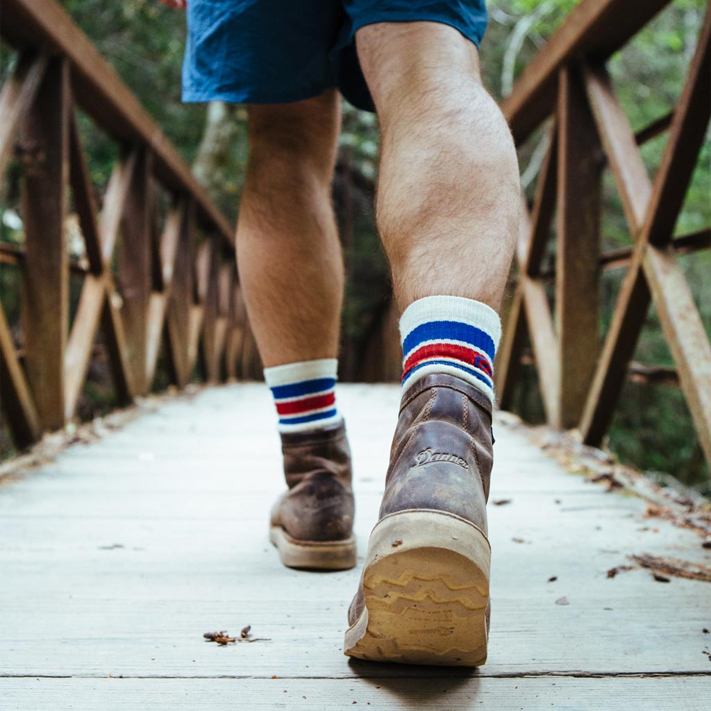Close up of hiker wearing Cloudline hiking socks walking across wood bridge.