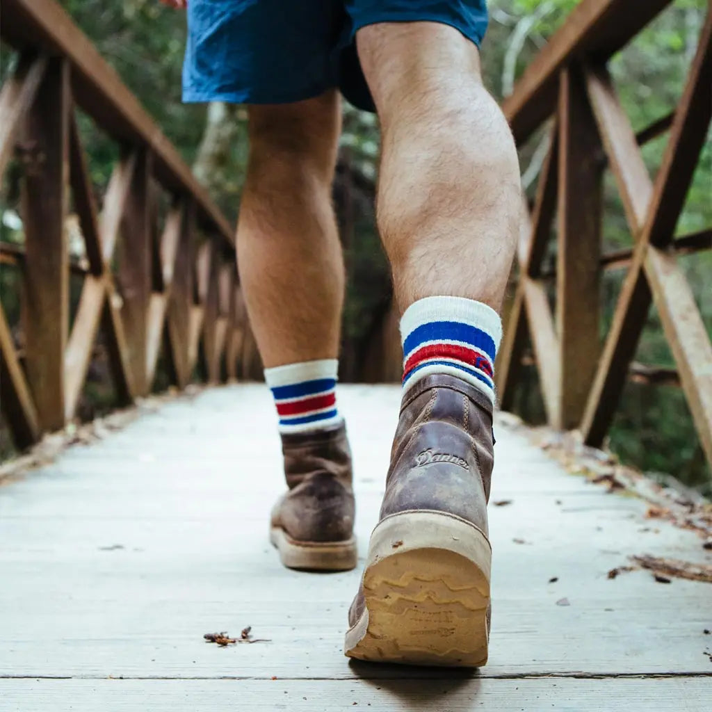Close up of hiker wearing Cloudline merino wool hiking socks walking across wood bridge.