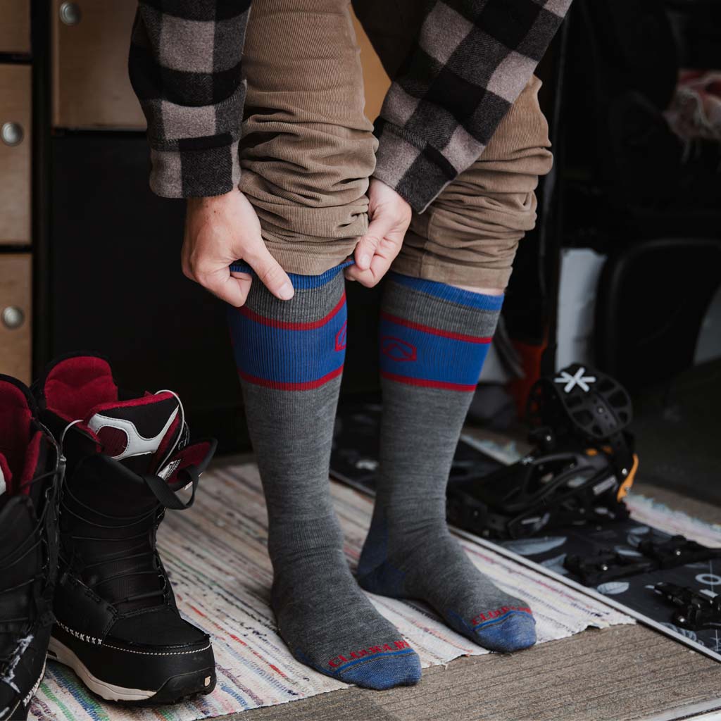 Man pulling on Cloudline snow socks inside camper van. 