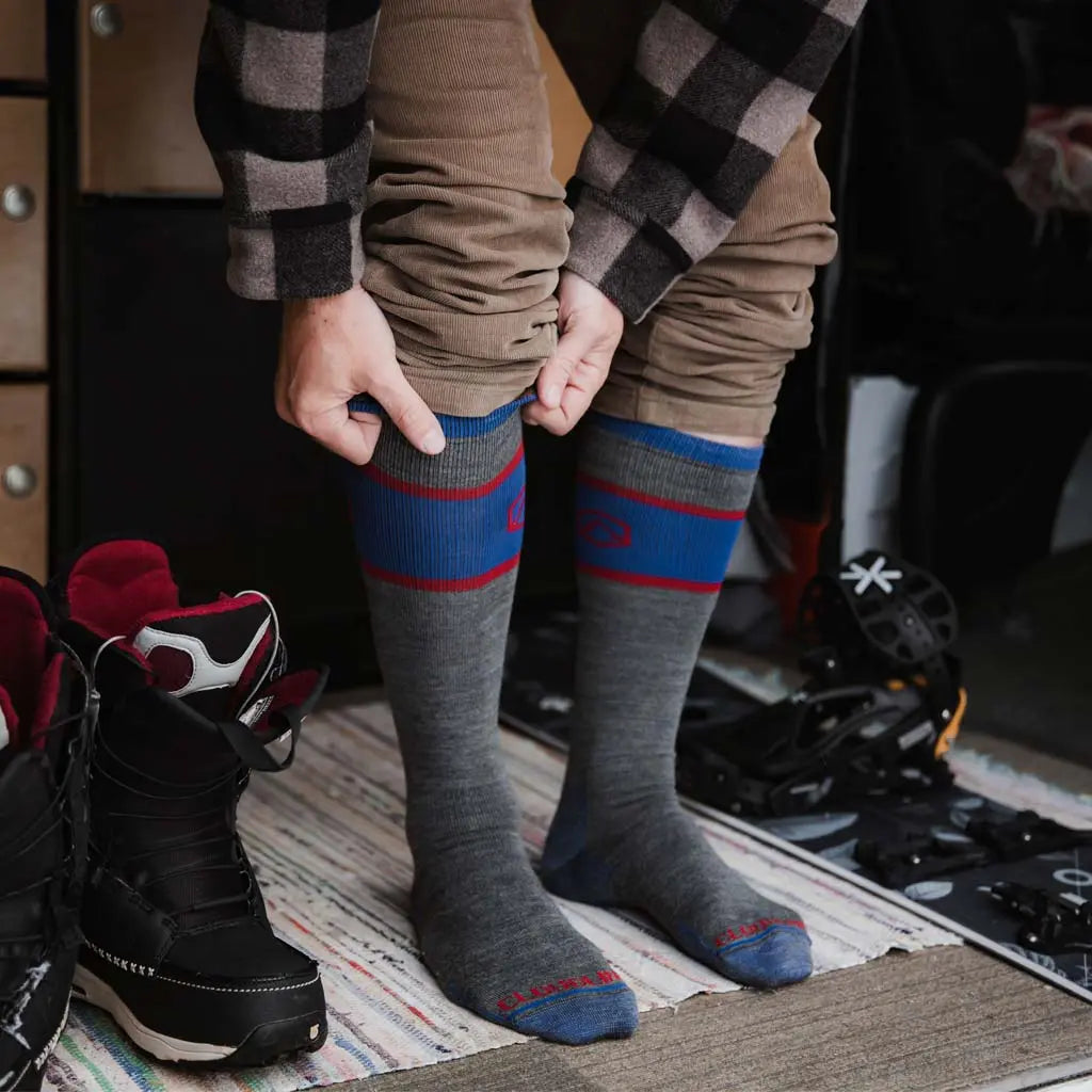 Man pulling on Cloudline merino wool snow socks inside camper van.