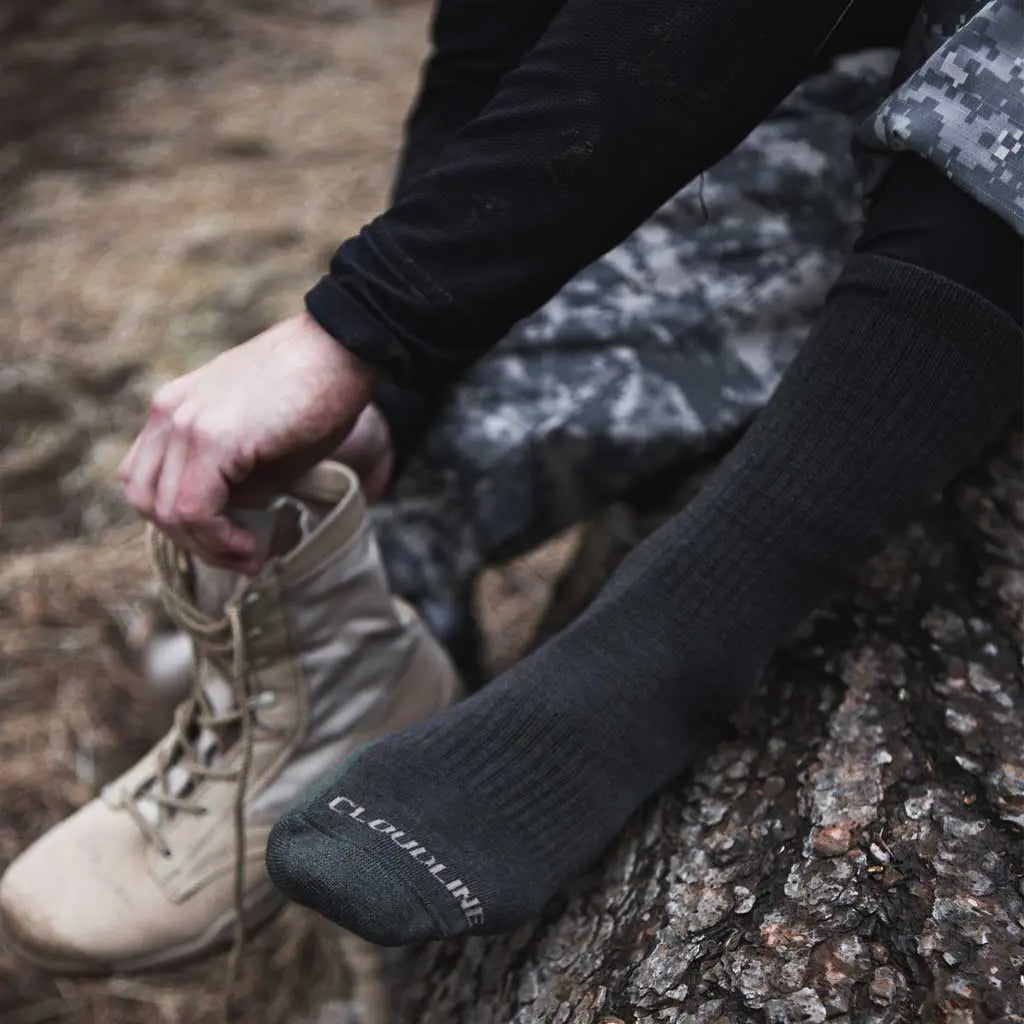 Man wearing Cloudline merino wool tactical socks putting on boots.