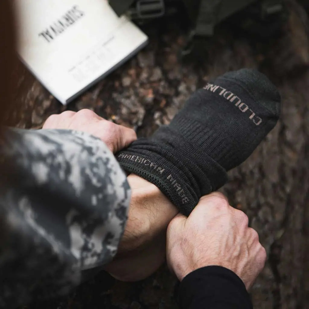 Close up of man pulling on Cloudline merino wool tactical socks.