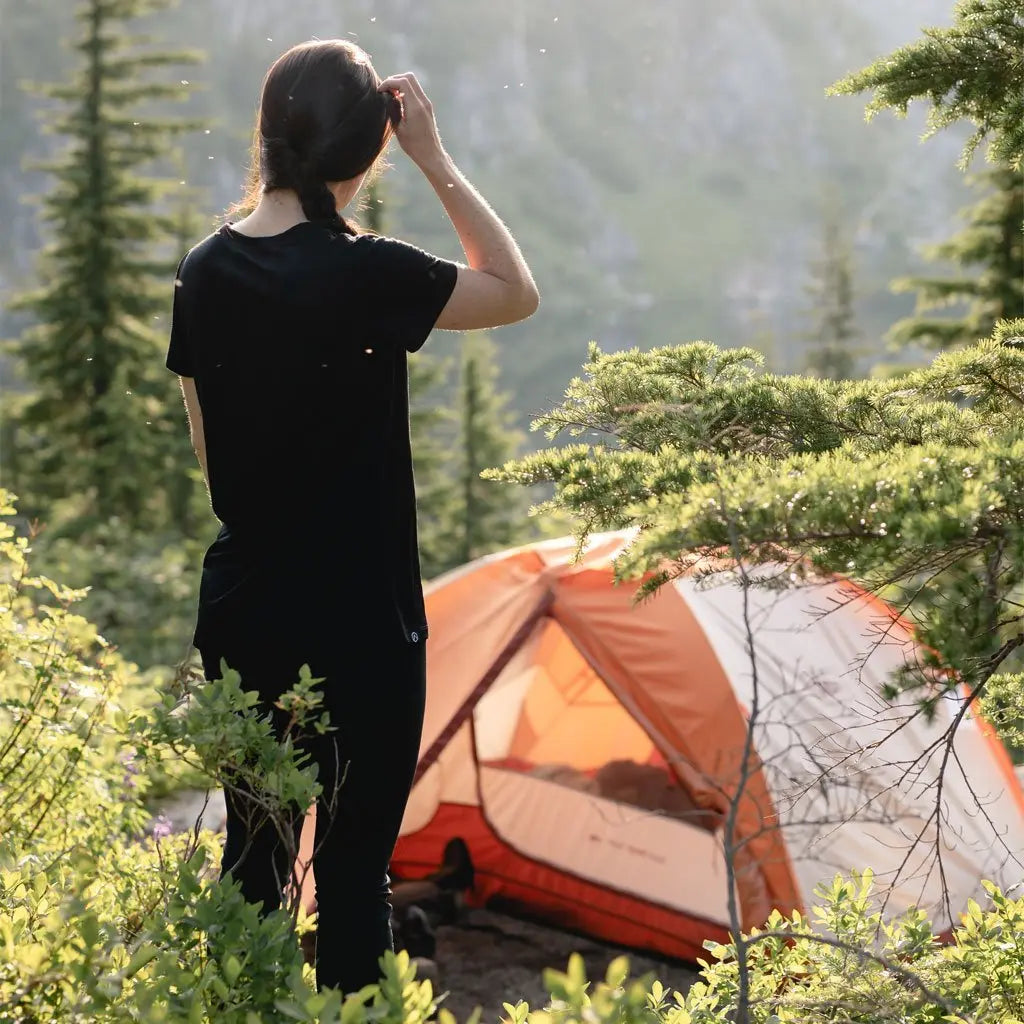 Women wearing Cloudline base layer tee standing in front of tent with back to camera.