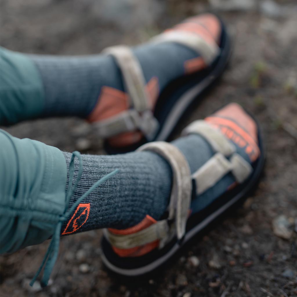 Close up of Cloudline logo on hiking socks worn by women resting by trail. 