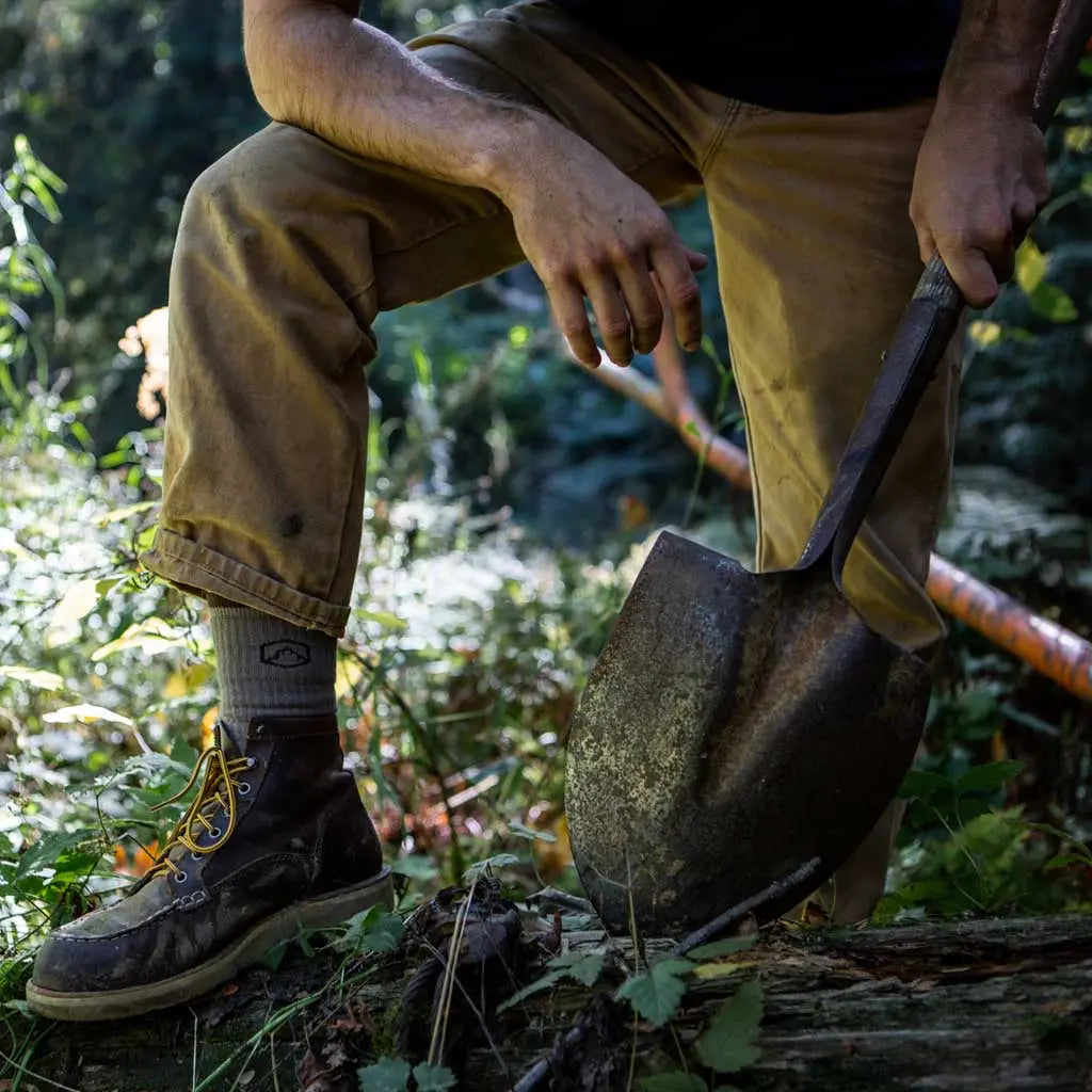 Man wearing Cloudline merino wool work socks holding shovel.