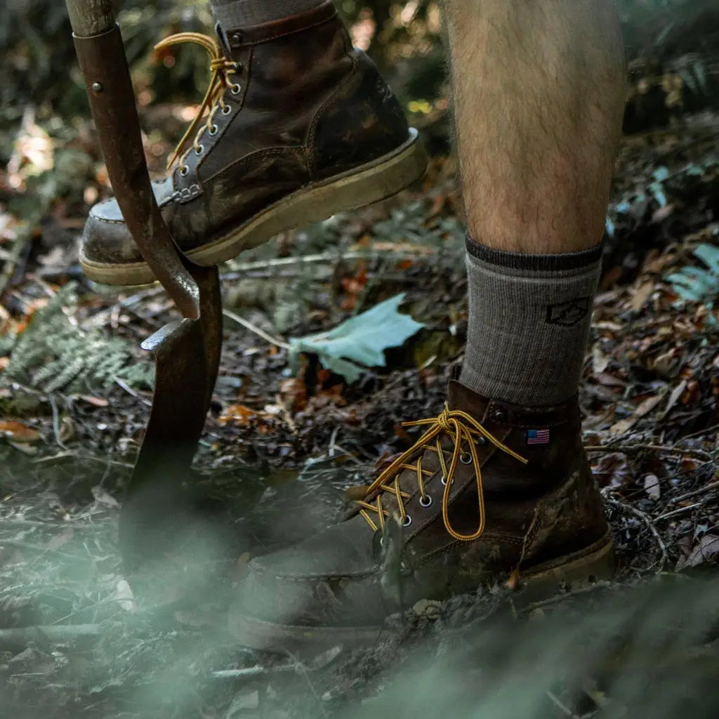 Man wearing Cloudline merino wool work socks digging with shovel.