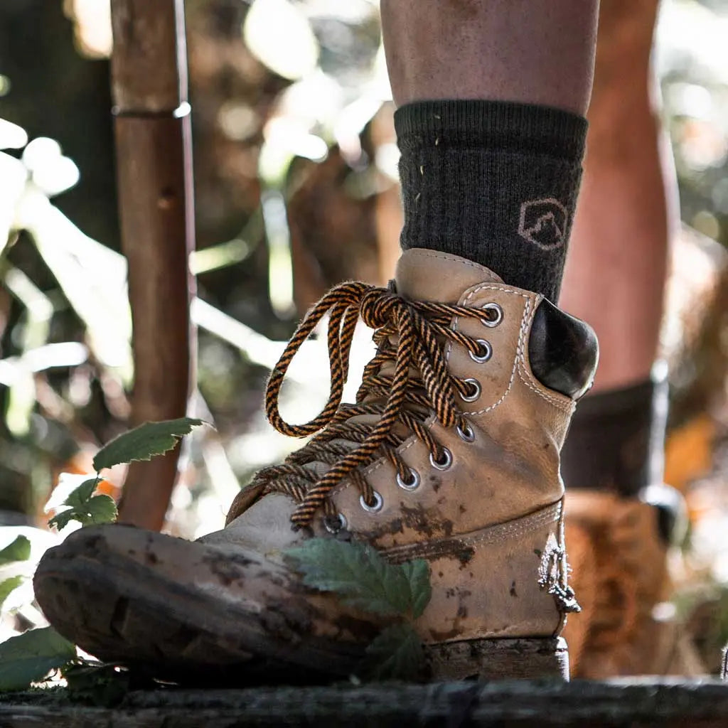Close up of man wearing Cloudline merino wool work socks standing in woods.