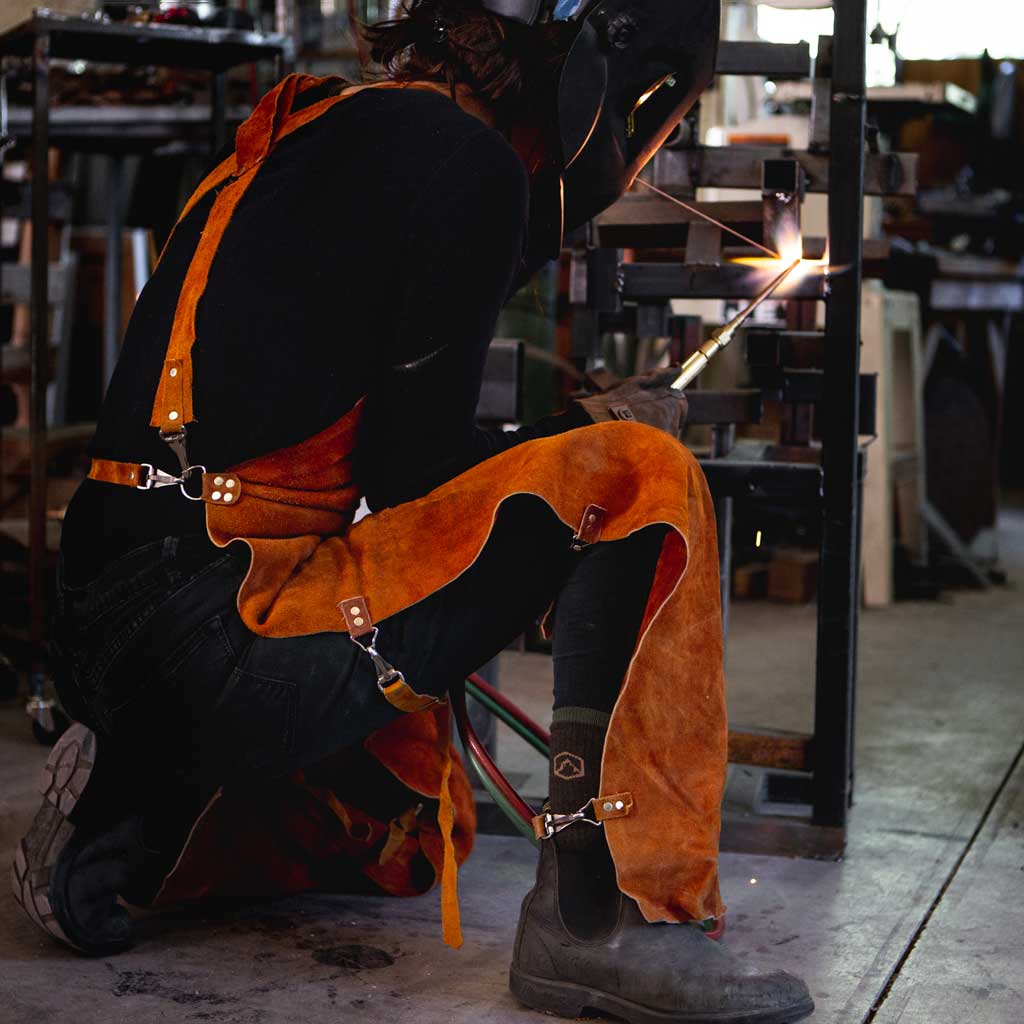 Women wearing Cloudline work socks and welding safety gear while welding.