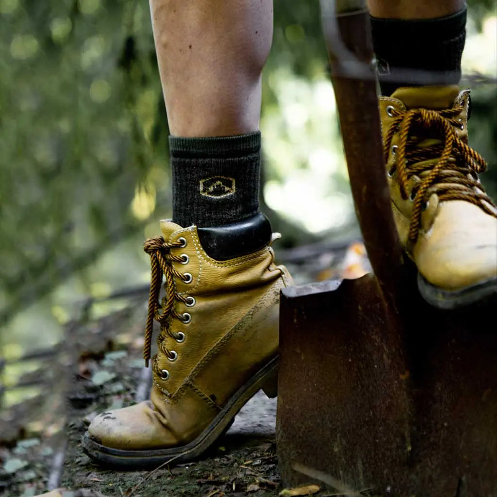 Women wearing Cloudline merino wool work socks digging hole with shovel.