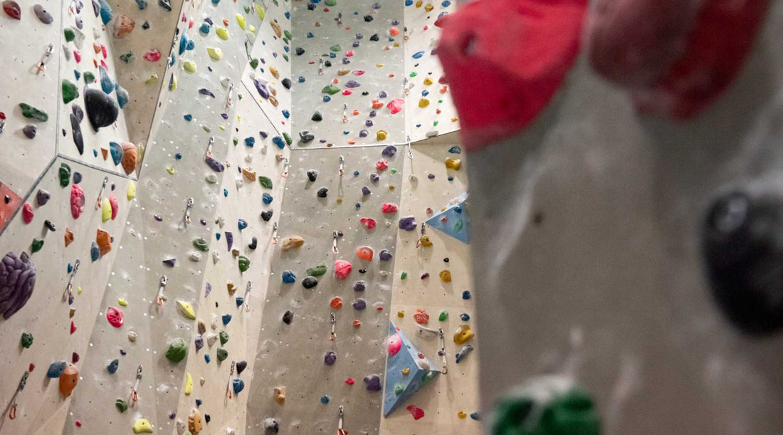 Looking up at a large indoor climbing gym wall.