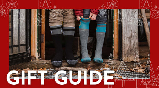 Couple standing in snowy cabin doorway wearing Cloudline socks