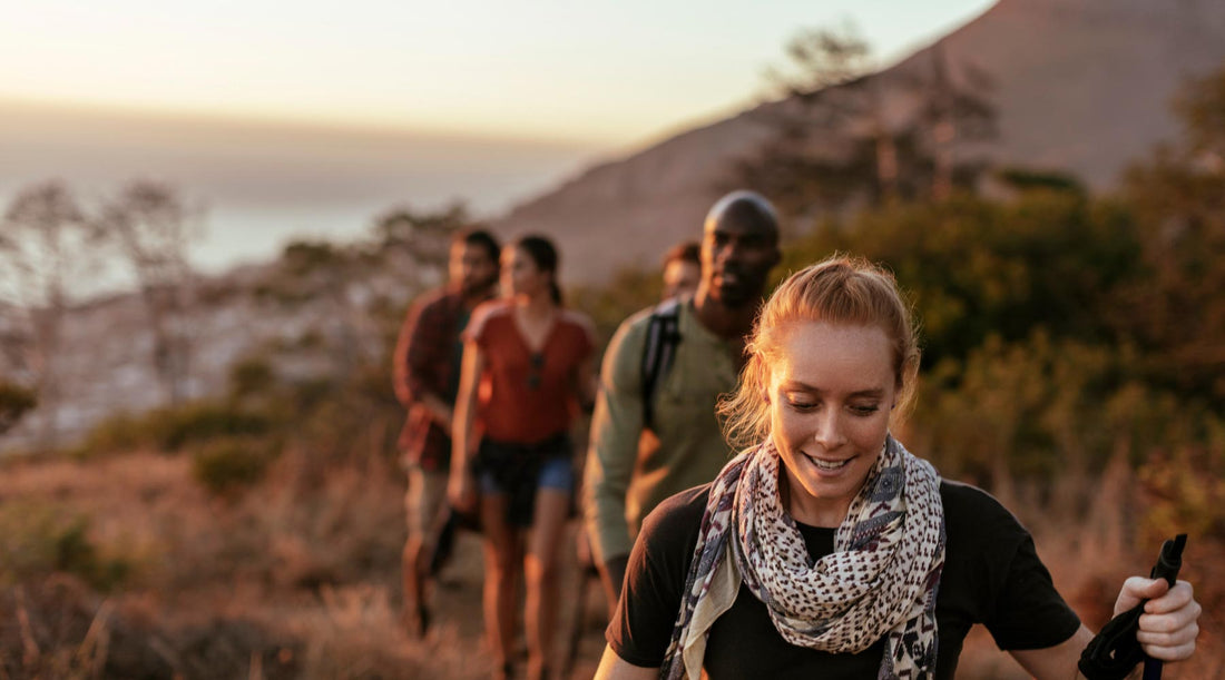 Group of hikers hiking along a trail as the sun sets.