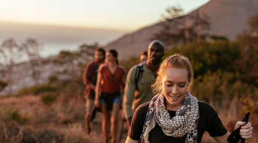 Group of hikers hiking along a trail as the sun sets.