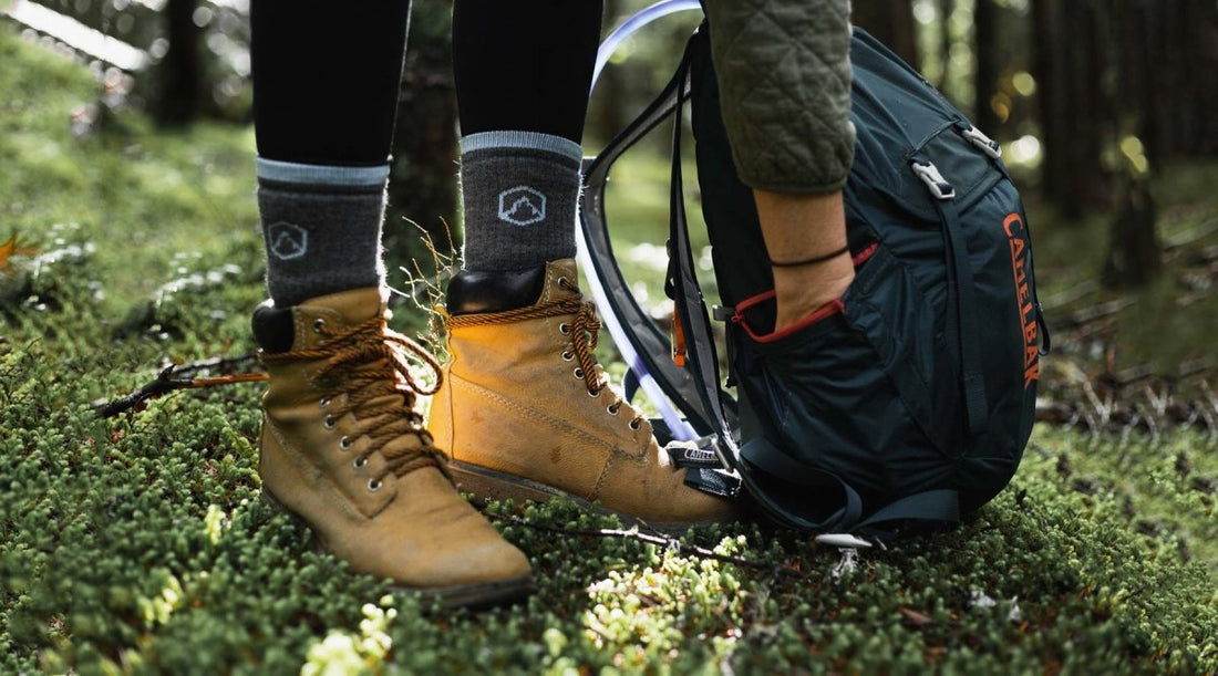Close up of hikers boots and hiking socks while bending down to reach in day pack.