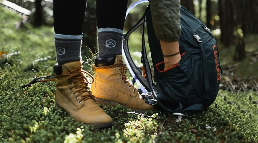 Close up of hikers boots and hiking socks while bending down to reach in day pack.