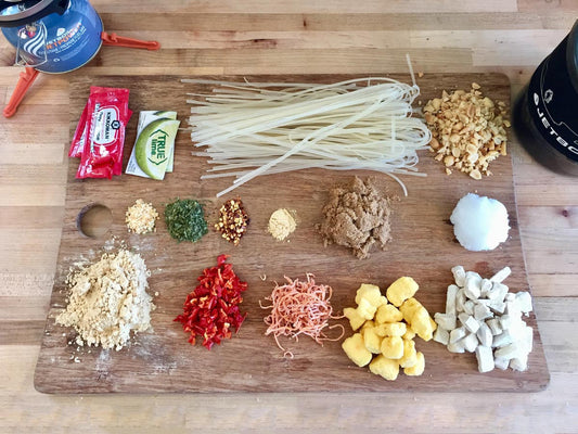 Backpacking pad thai ingredients laid out on cutting board at home.