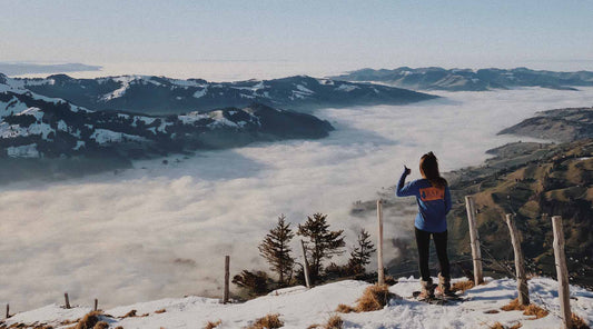 View from behind of a snowshoer looking out over a snow covered valley.