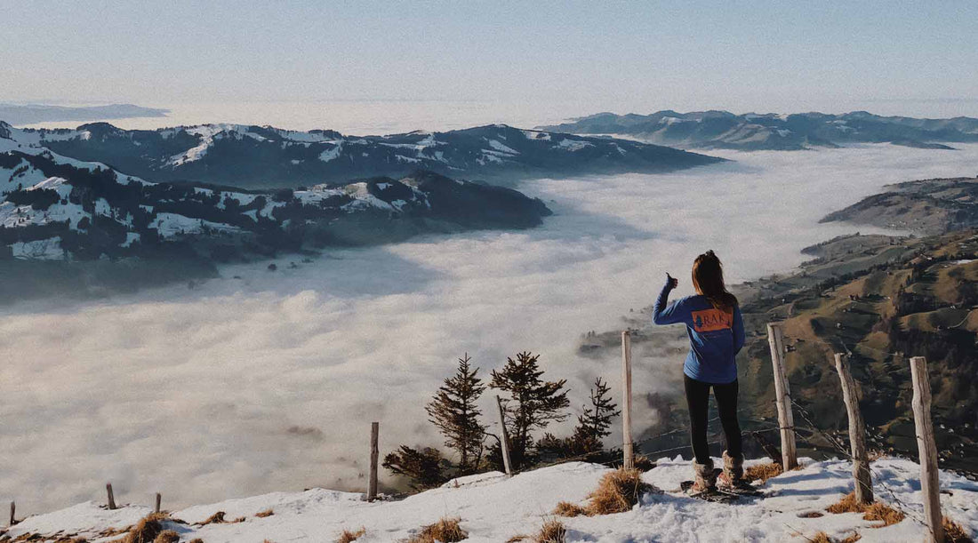 View from behind of a snowshoer looking out over a snow covered valley.