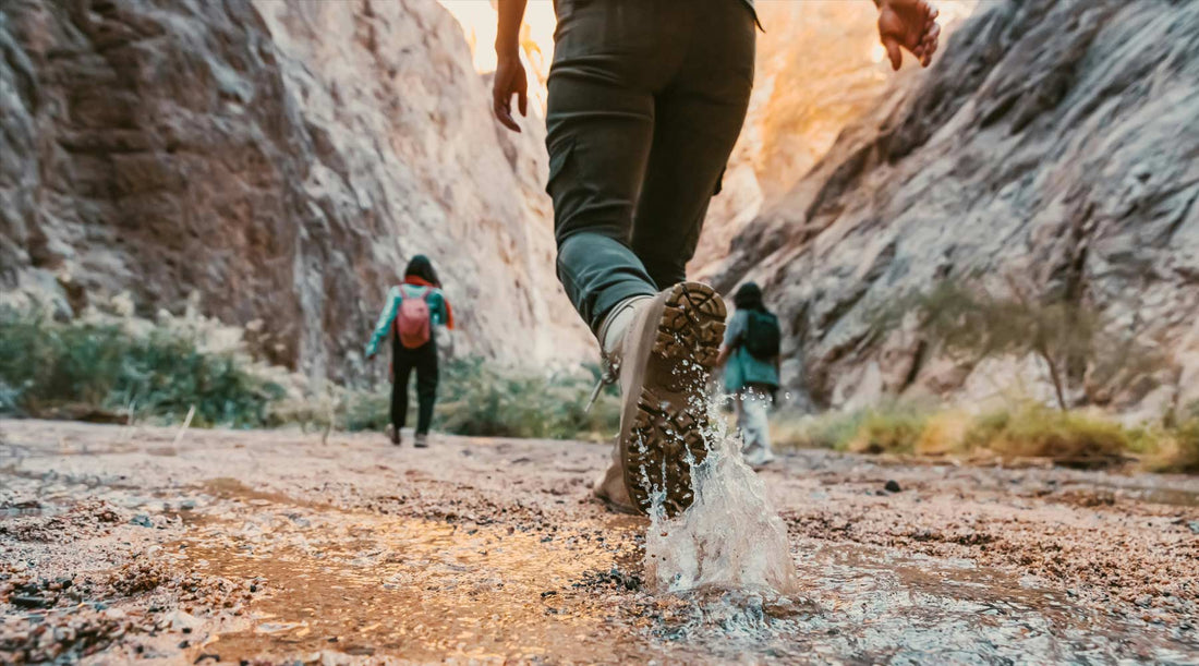 hikers walking through puddles in a slot canyon.