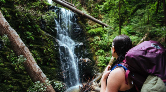 Backpacker looking at mossy waterfall.