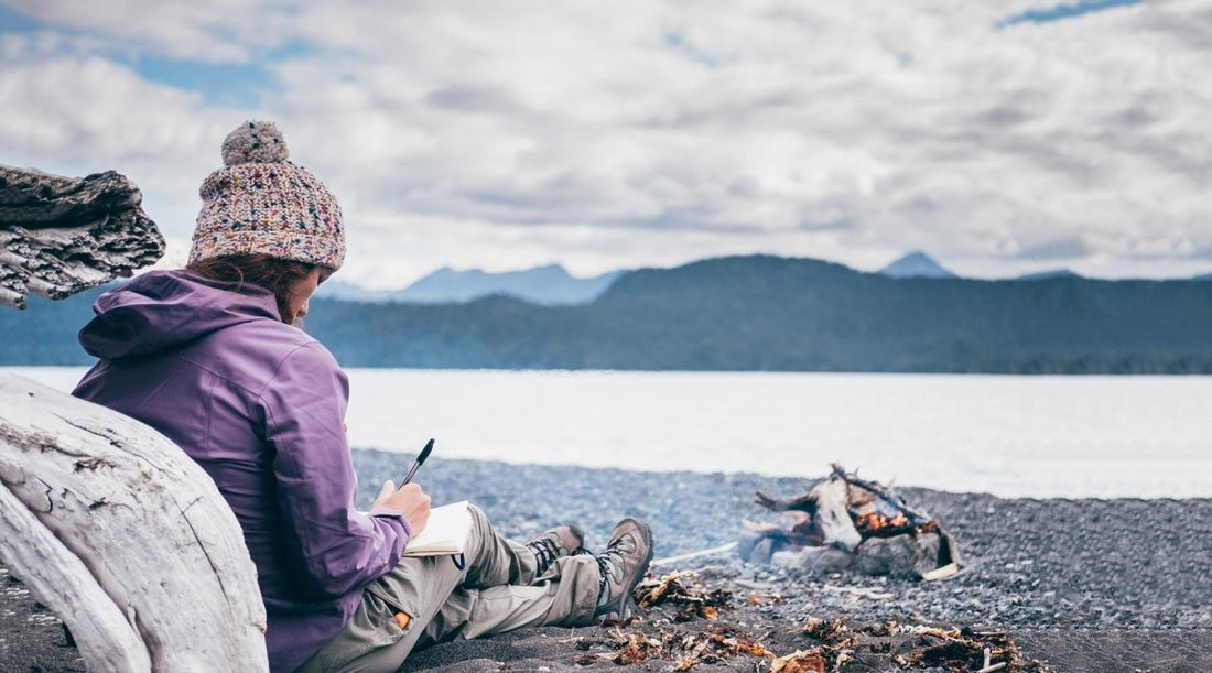 Woman sitting on the beach on a cloudy day and journaling.