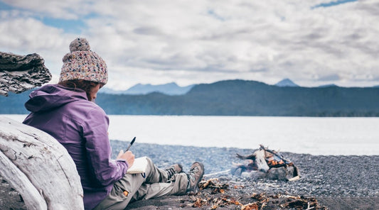 Woman sitting on the beach on a cloudy day and journaling.