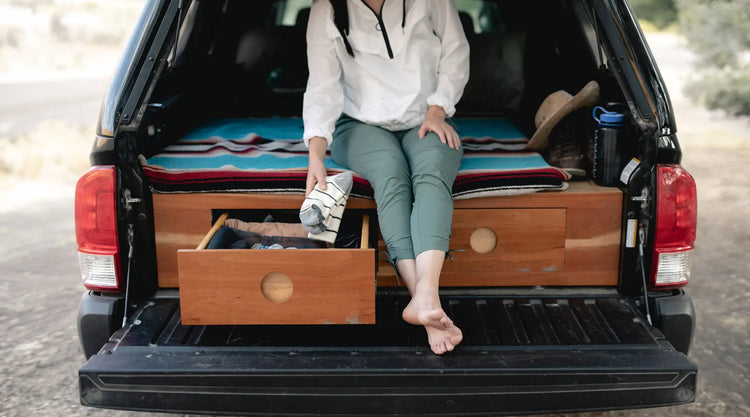 Women sitting in back of camper truck holding a pair of Cloudline hiking socks.