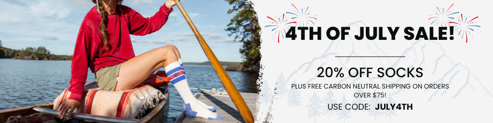  Women wearing Cloudline socks sitting in a canoe. 20% off with code JULY4TH 