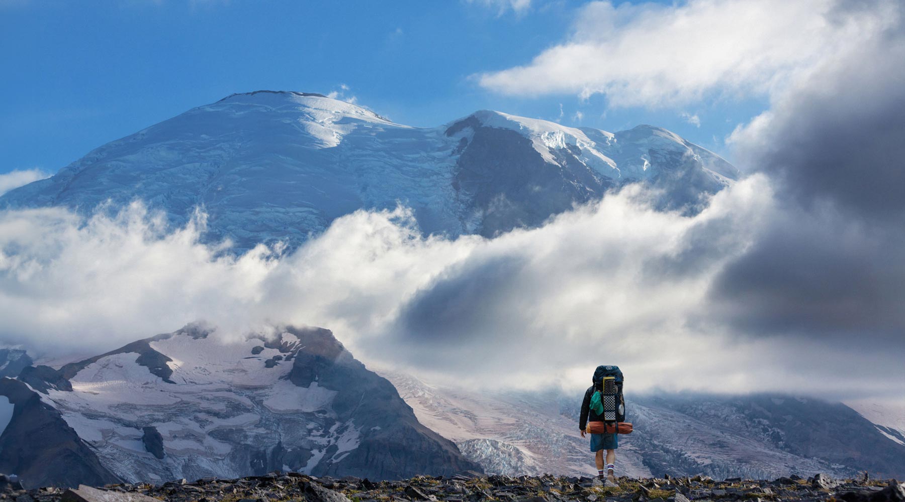 Backpacker wearing Cloudline socks looking at snowcapped mountain.