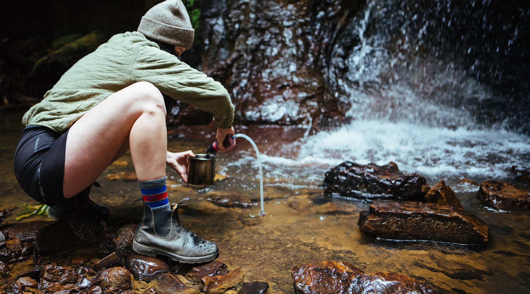 Women wearing Cloudline socks filtering water from a stream.