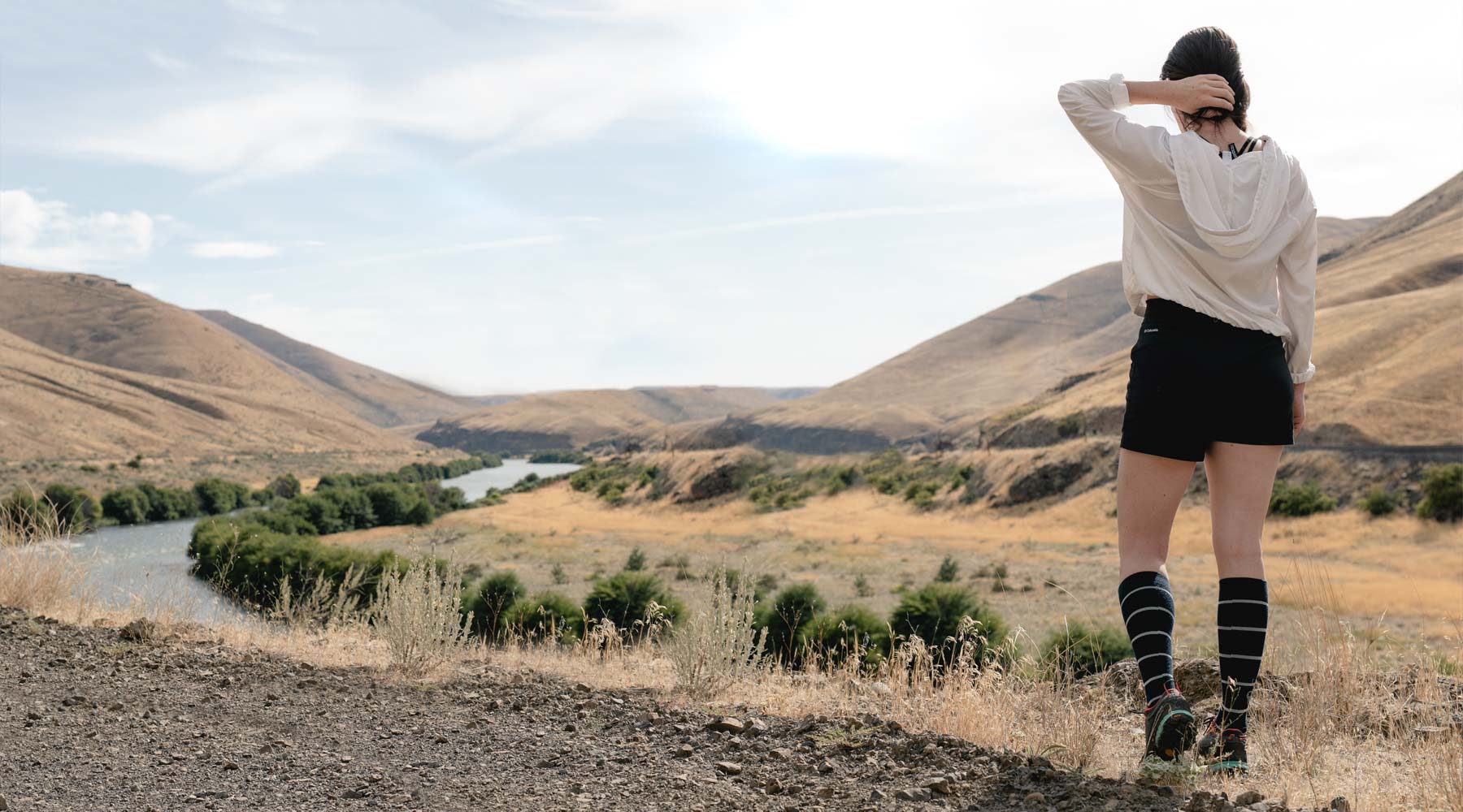 Women wearing Cloudline socks on the trail with river and mountains in the background