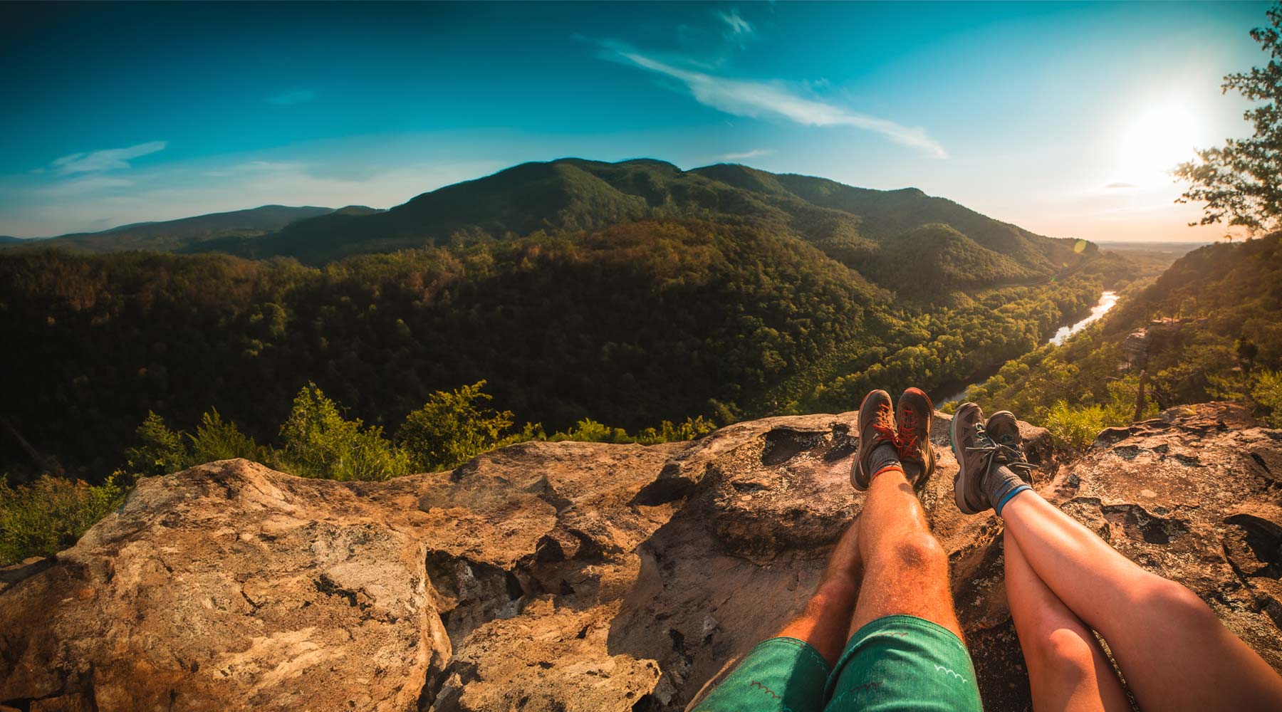 couple of hikers wearing cloudline socks sitting on cliff top enjoying epic view.