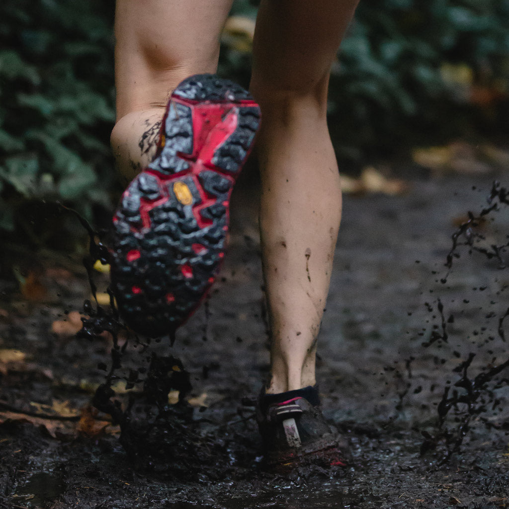 Trail runner wearing Cloudline socks on muddy trail. 