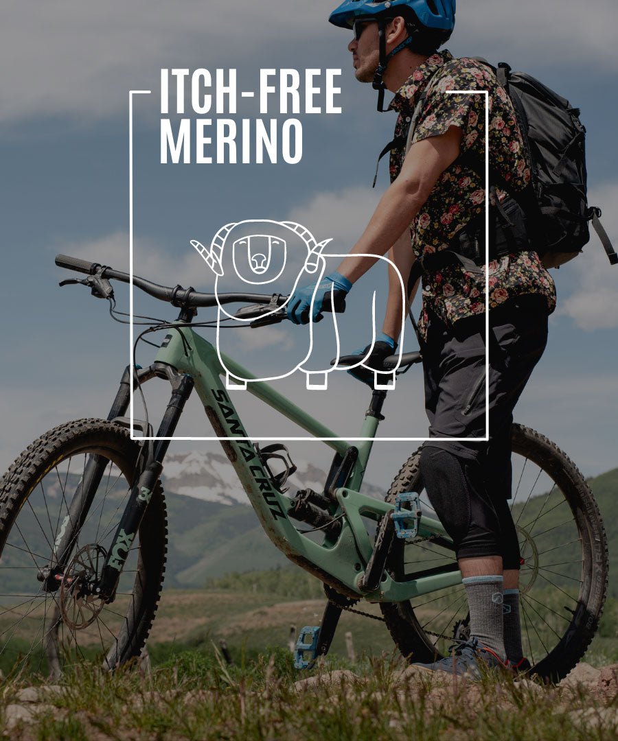 Mountain biker wearing Cloudline socks standing next to bike enjoying mountain view. 