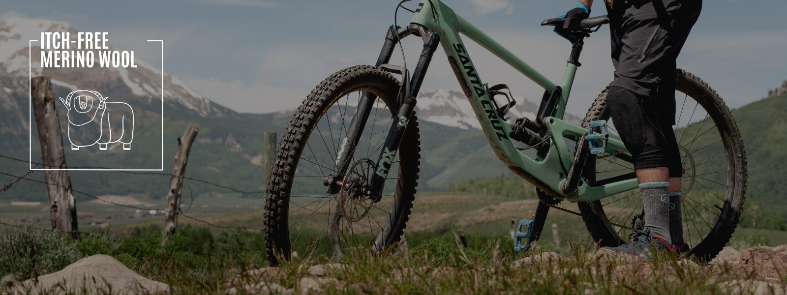 Mountain biker wearing Cloudline socks standing next to bike enjoying mountain view. 