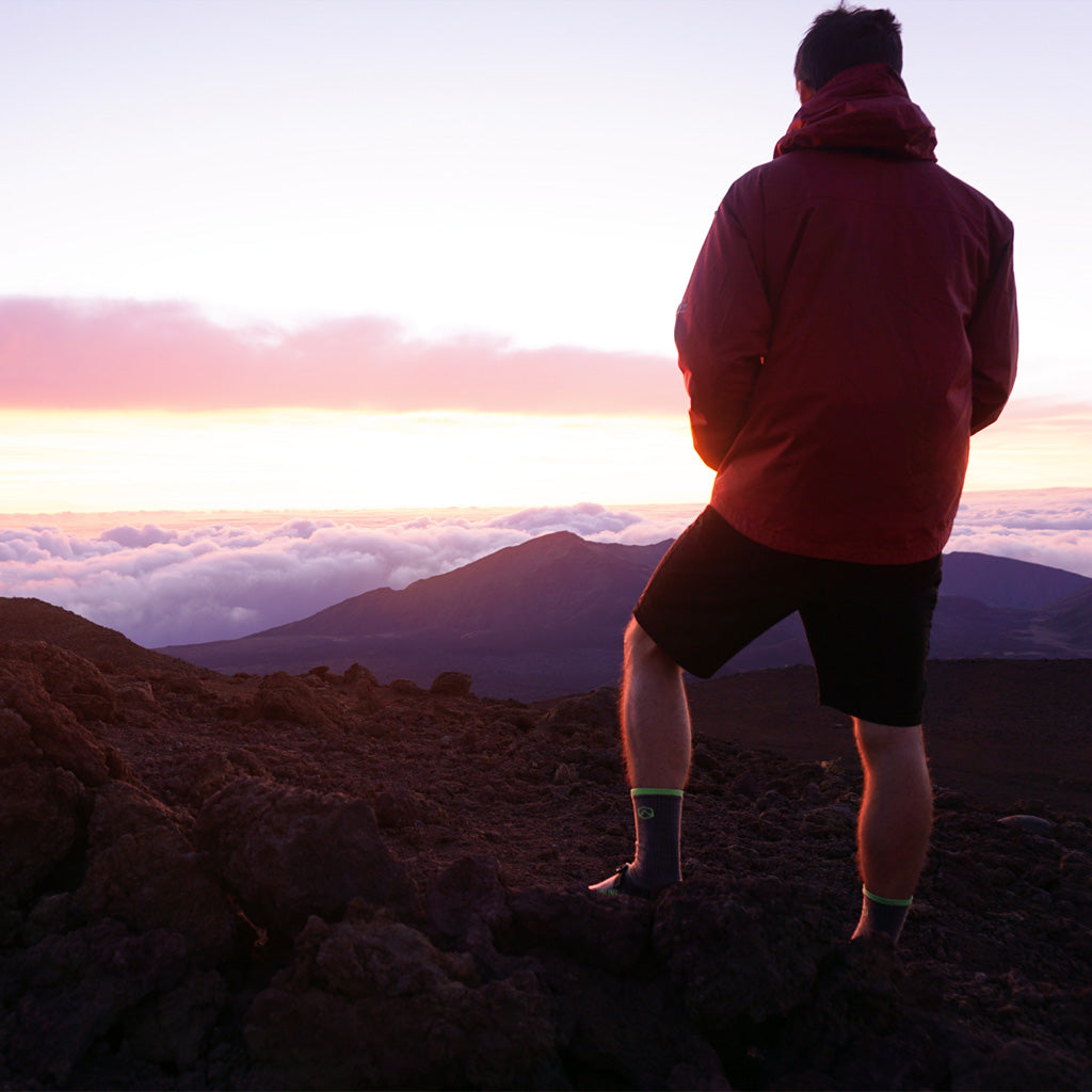 Hiker wearing Cloudline socks watching sunset on mountain top above the clouds. 