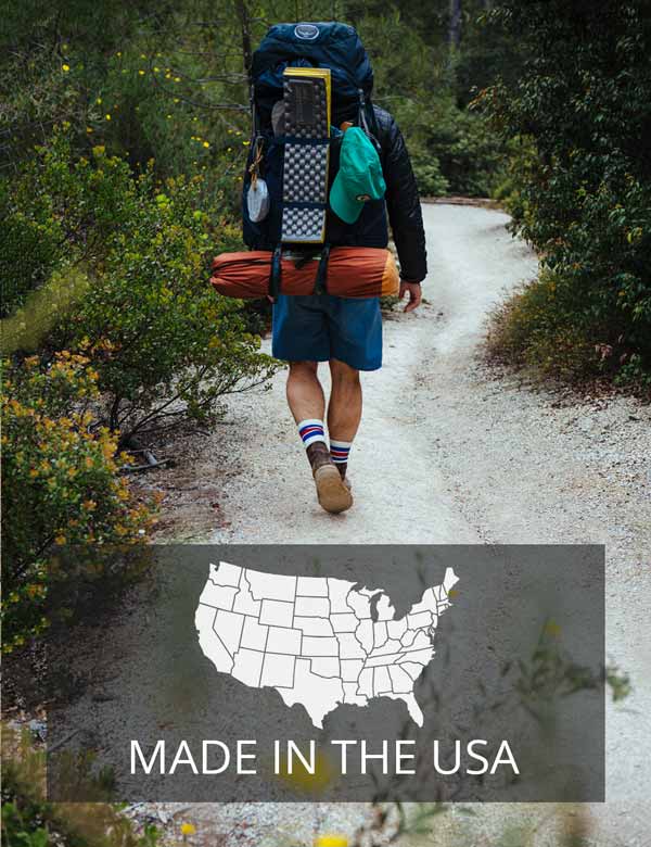 Backpacker with large pack hiking down trail wearing Cloudline socks. 